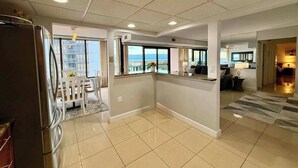 A spacious living area with a kitchen, dining area, and a view of the city. - Upscale ocean view condo with pool access & balcony - walk to beach, restaurants (Ocean City)
