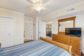 Ein Schlafzimmer mit Bett, Schminktisch, Fernseher und Deckenventilator.