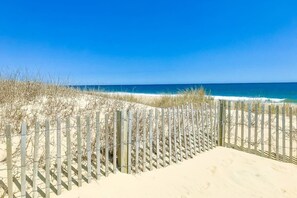 Ein Strand mit einer Holzlattenzäunung und Dünen.