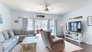 Ein Wohnzimmer mit Sofa, Sessel, Fernseher und Deckenventilator.