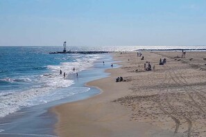 A beach with people, a lighthouse, and a clear sky. - Beach House 202, ocean view & balcony (Ocean City)