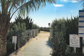 A wooden pathway leading to a building with signs indicating guest beach chairs and a no alcoholic beverages policy. - Beautiful beachfront condo with pools, ice rink, arcade, gym, & fast WiFi (Ocean City)