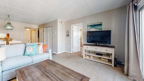 A living room with a sofa, coffee table, TV, and entertainment center. - Wight Bay South 449 (Ocean City)