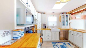 A kitchen with white cabinets, a wooden countertop, and a patterned rug. - Canal front home with free WiFi, deck, private dock, shared pool & tennis (Ocean City)