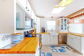 A kitchen with white cabinets, a wooden countertop, and a patterned rug. - Canal front home with free WiFi, deck, private dock, shared pool & tennis (Ocean City)