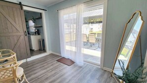 Una habitación con puerta corredera estilo granero, una zona de comedor con mesa y sillas, un espejo grande y vistas al exterior.