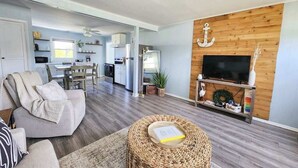 Una sala de estar moderna con un sofá, una mesa de centro, un televisor y una pared de madera con una decoración de ancla.