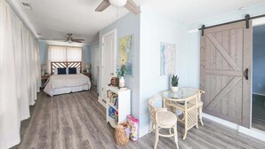 Un dormitorio con cama, escritorio, silla, ventilador de techo y una puerta corredera de estilo granero.