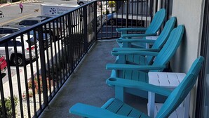 Un balcone con poltrone color acquamarina, vista sull'oceano e un edificio con balconi.