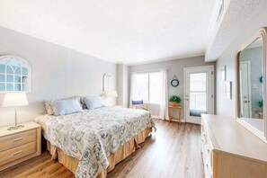 Une chambre à coucher avec un lit, des tables de chevet, une commode, une fenêtre et une porte.
