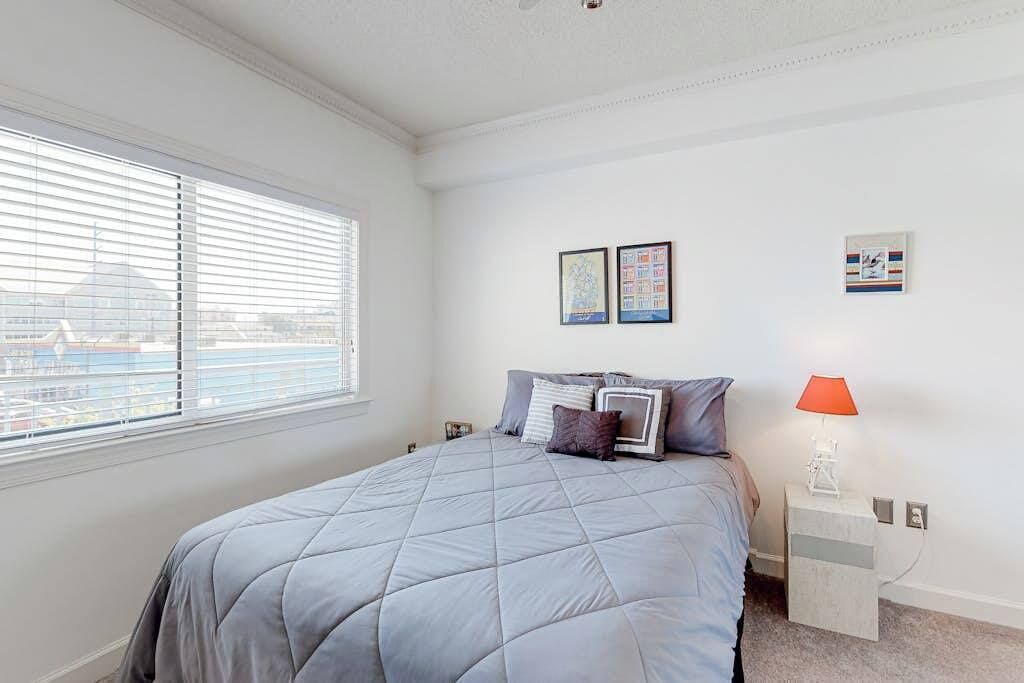 A bedroom with a bed, a nightstand, a lamp, and two framed pictures on the wall.