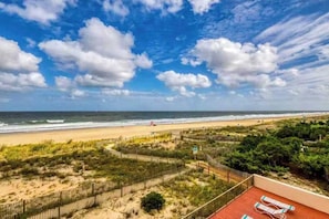 A beach view with a wooden deck and lounge chairs. - Sixth floor oceanfront condo with beach access (Ocean City)