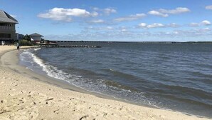 A beach with a building on the left, a pier in the distance, and a clear sky. - Sunset Island - 59 Island Edge (Ocean City)