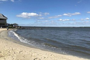 A beach with a building on the left, a pier in the distance, and a clear sky. - Sunset Island - 59 Island Edge (Ocean City)