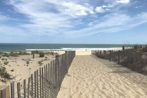 A sandy beach path leading to the ocean, with a wooden fence on one side and a clear view of the sea. - Canal-front getaway with private hot tub, large deck & firepit - dog-friendly (Ocean City)