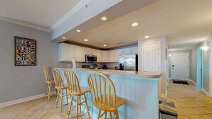 Una cocina moderna con barra, sillas de madera y piso de baldosas.