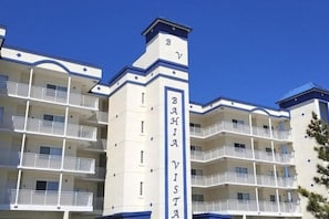 A multi-story hotel with balconies, a prominent vertical sign, and a blue roof. - Bahia Vista II 305 (Ocean City)