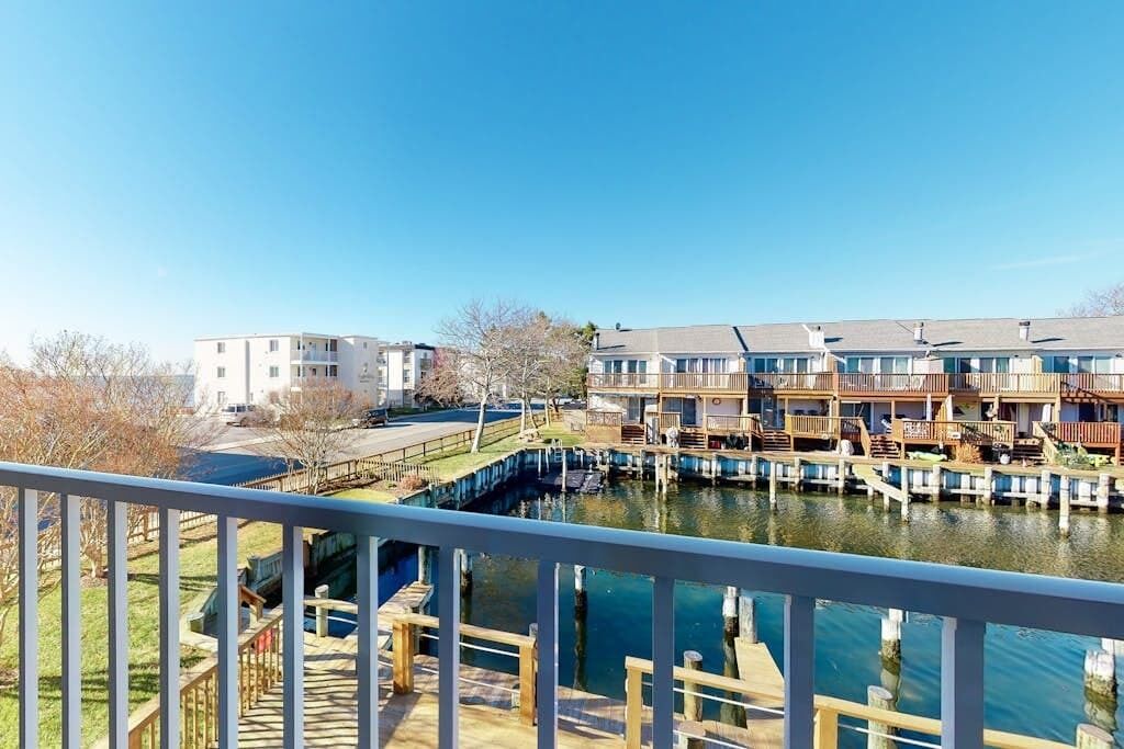 A waterfront residential area with multi-story buildings, a dock, and a clear blue sky.