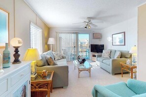A living room with a ceiling fan, two sofas, a TV, and a glass coffee table. - Waterfront Condo - Shared dock - Free WiFi, Partial AC, Washer/Dryer (Ocean City)