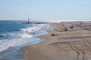 A beach with a lighthouse, sandy shore, and people. - Blue Marlin 402 (Ocean City)