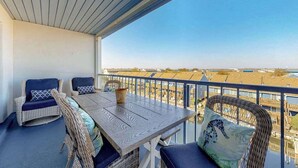 A balcony with a table and chairs, a view of the beach, and a railing. - Blue Marlin 402 (Ocean City)