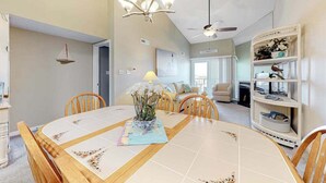 A dining area with a wooden table, chairs, a chandelier, and a bookshelf. - Blue Marlin 402 (Ocean City)