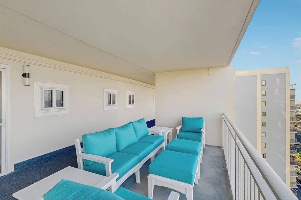Un balcon avec un ensemble de meubles de salon comprenant un canapé et une table, une balustrade et une vue sur un immeuble.