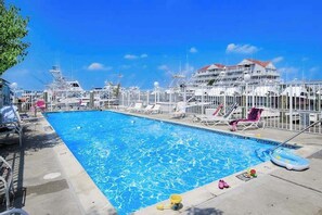 A swimming pool with lounge chairs and a marina in the background. - Charming bayfront condo in Old Town with balcony, WiFi, AC, & shared pool (Ocean City)
