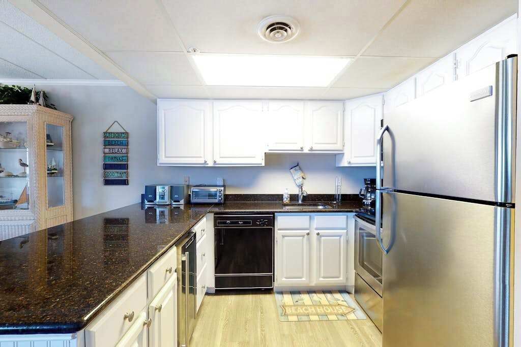 A kitchen with white cabinets, a stainless steel refrigerator, a dishwasher, and a microwave.