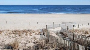 A beach with a wooden fence and sand dunes. - Waikiki 102 (Ocean City)