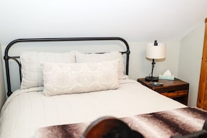 A bed with a headboard, pillows, a bedside table with a lamp, and a tissue box. - Trailside Chalet at Pleasant Mt. (Bridgton)