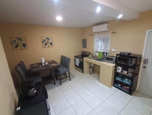 A compact kitchen with a dining area, a microwave, a stove, and a small trash bin.