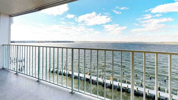 A balcony with a metal railing overlooking a body of water and a distant shoreline. - Thunder Island 28A (Ocean City)