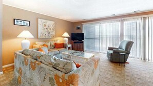 A living room with a sofa set, a television, and a chair. - Thunder Island 28A (Ocean City)