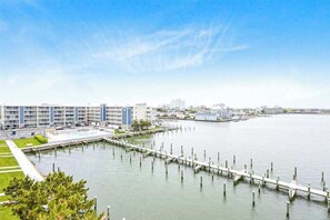 A waterfront hotel with a dock, a parking area, and a grassy lawn. - Thunder Island 25A (Ocean City)