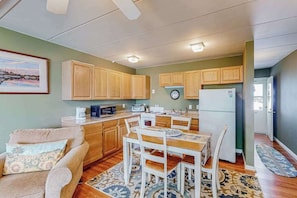 A compact kitchen with wooden cabinets, a dining table, and a sofa. - Bay Colony 36 (Ocean City)