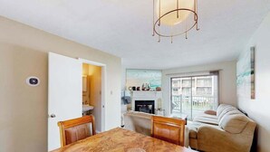 A dining area with a marble table, wooden chairs, a chandelier, a fireplace, and a sofa. - Dawn's Cove F (Ocean City)