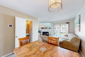 Un comedor con una mesa de mármol, sillas de madera, un candelabro, una chimenea y un sofá.