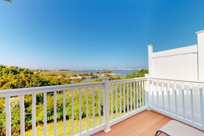 A balcony with a white railing overlooking a body of water, greenery, and distant buildings. - Seaside Village - #3 (West Ocean City)