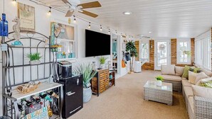 Un salón amplio con ventilador de techo, televisor de pantalla plana, sofá y mesa de centro.