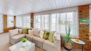 Un salón amplio con un sofá modular grande, una mesa de centro de cristal y una pared de ladrillo decorativa.