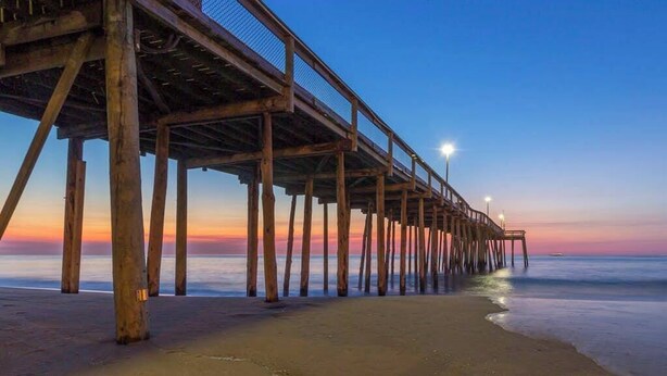 Un muelle de madera que se adentra en el agua, bajo un cielo despejado.