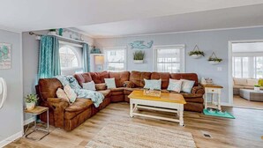 Una sala de estar con un sofá modular, una mesa de centro de madera y una mesita auxiliar.
