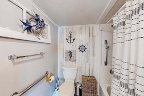 Une salle de bain au décor rustique, avec des toilettes blanches, une douche et une couronne décorative accrochée au mur.
