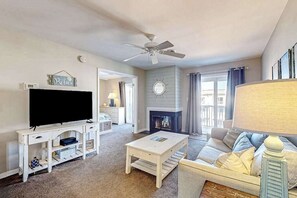 A living room with a television, white furniture, a fireplace, and a ceiling fan. - Lucayan 18 (Ocean City)