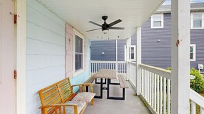 A covered porch with a ceiling fan, a wooden bench, and a picnic table. - Comfortable condo near the beach & downtown with private balcony (Ocean City)