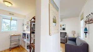 A compact living space with a kitchenette, a grey sofa, a mirror, and a wall-mounted shelf. - Comfortable condo near the beach & downtown with private balcony (Ocean City)