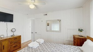 A bedroom with a bed, wooden dresser, vanity, mirror, and a ceiling fan. - Comfortable condo near the beach & downtown with private balcony (Ocean City)