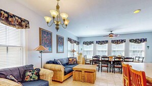 A living room with a sofa, ottoman, dining table, chairs, and a chandelier. - Coastal retreat with beach and shared pool - balconies, AC, & W/D (Ocean City)