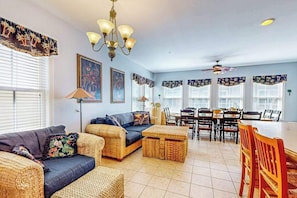 A living room with a sofa, ottoman, dining table, chairs, and a chandelier. - Coastal retreat with beach and shared pool - balconies, AC, & W/D (Ocean City)